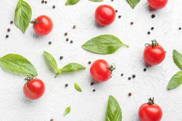 Composition with ripe cherry tomatoes, basil leaves and peppercorn on light background