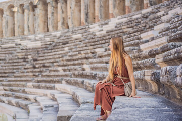 Naklejka premium Woman tourist explores Aspendos Ancient City. Aspendos acropolis city ruins, cisterns, aqueducts and old temple. Aspendos Antalya Turkey. turkiye