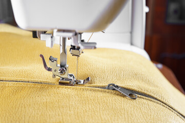 Modern sewing machine with yellow velours fabric. Special presser foot and zipper close up. Sewing process clothes, curtains upholstery. Business, hobby, handmade, zero waste, repair concept