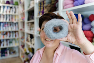 Smiling woman looking through the ball of mohair yarn while holding it in her hand