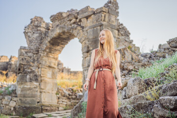 Woman tourist explores Aspendos Ancient City. Aspendos acropolis city ruins, cisterns, aqueducts and old temple. Aspendos Antalya Turkey. turkiye