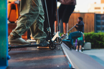 Skate park with kids on a kick scooter doing tricks and stunts, boys in a skate park riding bmx...