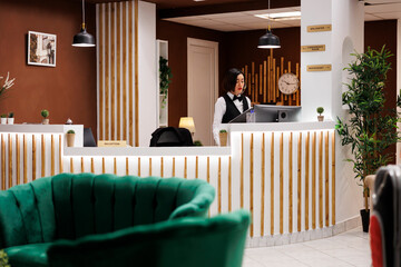 Hotel concierge writing booking form at front desk, preparing to help guests with accommodation at...