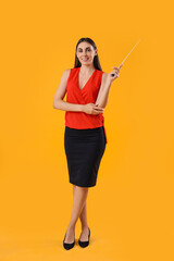 Young female teacher with pointer on yellow background