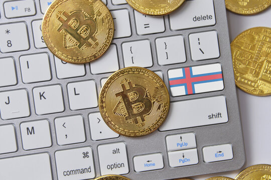 national flag of faroe islands on the keyboard with bitcoin coins on a grey background.