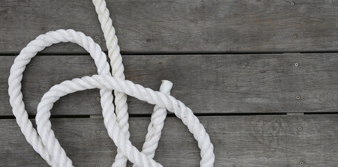 White boat rope attached to a wooden dock with dark water below