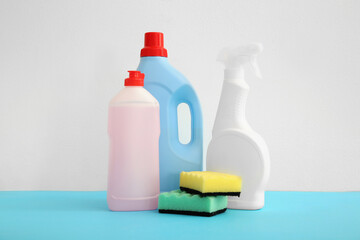 Bottles of detergent and sponges on blue table against white background