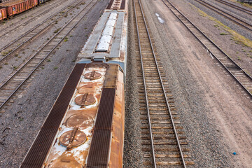 Wide view of rusty train cars and railroad tracks in a train yard. 