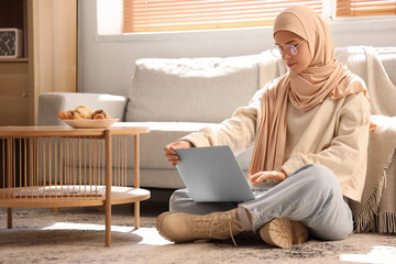 Young Muslim woman with laptop at home