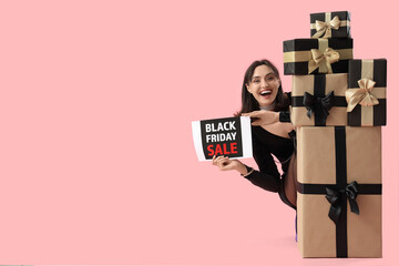 Young woman with gifts on pink background. Black Friday sale