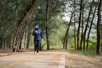 Happy cheerful Middle-aged Asian Muslim woman practicing exercise and stretching and enjoy jogging at the park close up with copy space. Modern muslim woman lifestyles and diversity concept.