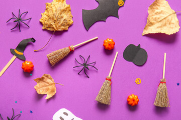 Halloween composition with brooms, pumpkins, leaves and spiders on purple background