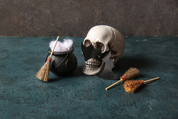 Halloween composition with brooms, skull and cauldron on black grunge background