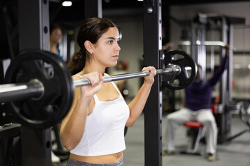 Sportswoman doing exercises with a barbell in the gym
