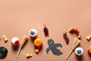Halloween composition with candy bugs, eyeballs and brooms on brown background
