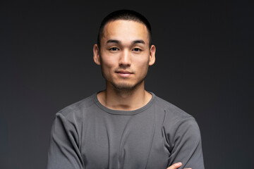 Portrait of smiling, attractive Asian man standing isolated on black background, looking at camera