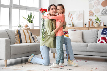 Obraz premium Little boy with carnation flowers hugging his mother at home. Veterans Day celebration