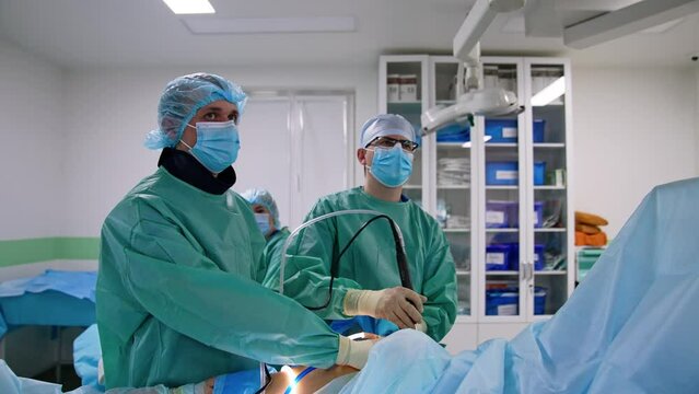 Professional surgeons use advanced laparoscopic surgical devices. Doctors are focused on the monitor in front of them.