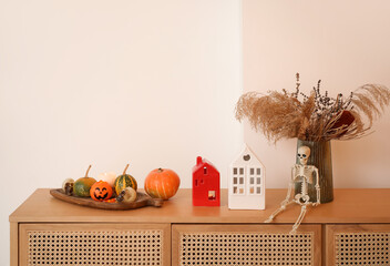 Vase with pampas grass, candle holders and Halloween decor on drawers in room