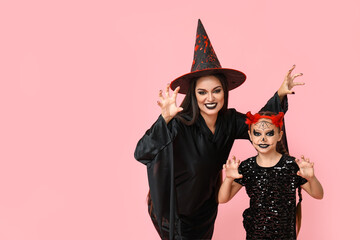 Scary little girl with her mother dressed for Halloween on pink background