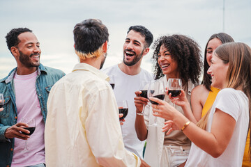 Group of young adult best friends talking, laughing and having fun together on a birthday party celebration. Excited people cheering and drinking wine glasses on a festive social meeting at weekend