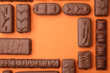 Different tasty chocolate bars on orange background, flat lay. Space for text
