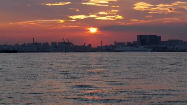 雲の隙間から観える丸い夕日が美しい東京湾の風景。