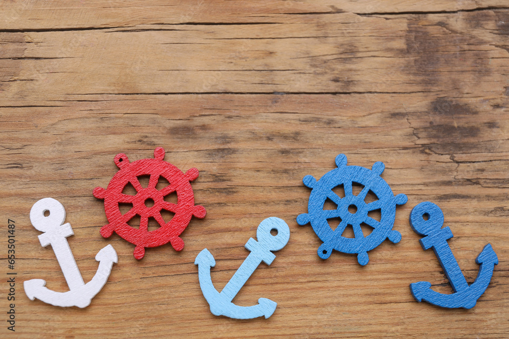 Wall mural Anchor and ship wheel figures on wooden table, flat lay. Space for text