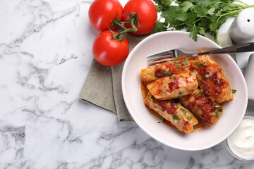 Delicious stuffed cabbage rolls cooked with homemade tomato sauce on white marble table, flat lay. Space for text