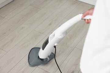 Man cleaning floor with steam mop at home, closeup