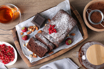 Tasty chocolate sponge cake served on wooden table, flat lay