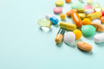 Many different pills on light blue background, closeup. Space for text