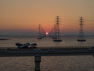 High-voltage transmission tower and sunset over the sea