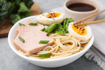 Delicious ramen with meat on light grey table, closeup. Noodle soup