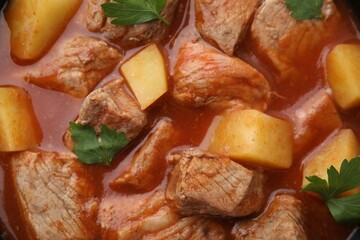 Delicious goulash with parsley as background, closeup