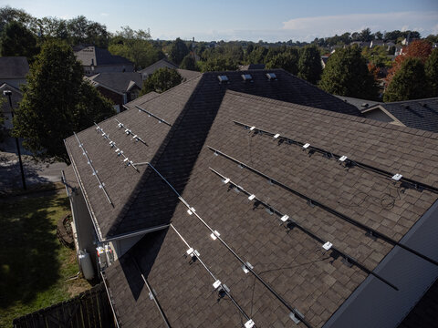 Racking And Power Optimizers Installed On The Roof Of Suburb House With Shingles Prepared For Putting Solar Panels