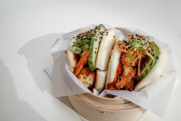Bao buns, steamed wheat flour-based, leavened dough wrap and filled with fried Chicken, on bamboo...