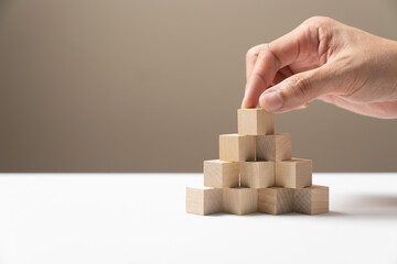 Hand putting wood cubes arrange in a pyramid shape mock-up