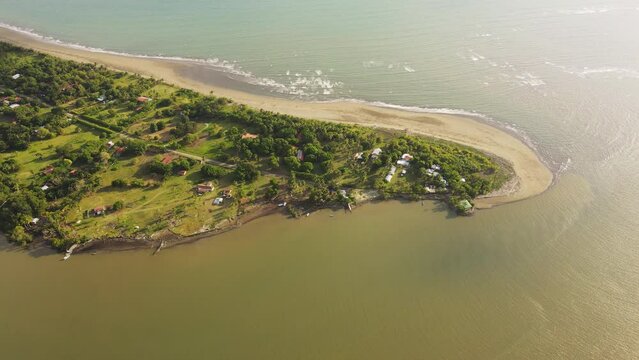 Aerial view of a peninsula in Costa Rica, showcasing a strong contrast between the golden sunlight and the lush greenery. This scenic landscape is located in Zancudo, Costa Rica.