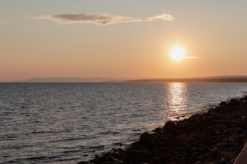 Fototapeta na wymiar vue du bord d'une plage rocailleuse en bord de mer lors d'un coucher de soleil d'été
