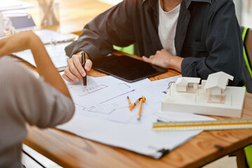 A male architect or interior designer is consulting on building plans and designs with a client.