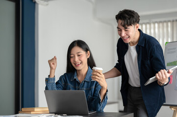 Two happy Asian businesspeople are celebrating their project success together, screaming with joy