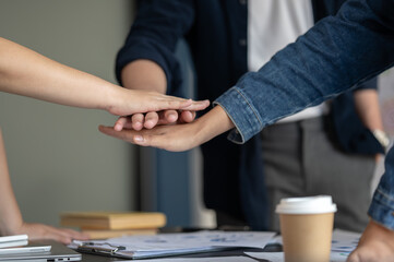 Close-up image of a startup team worker putting their hands together as a team after the meeting.
