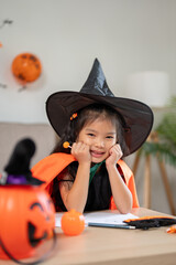 A cute little girl in a Halloween costume with a lollipop in her hand is sitting in the living room.
