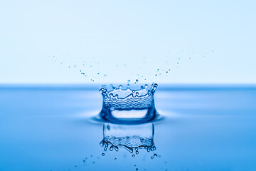 Group of water droplets fall and bounce on a water surface