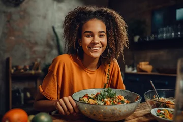 Fotobehang Happy young multiracial woman mixing bowl of fresh salad © Hector Pertuz