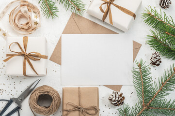 Christmas gift boxes, craft paper envelope and blank form, ribbons and scissors on a white...