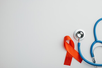 Stethoscope and red AIDS ribbons from a top view, isolated on white. Symbolizing hope and support...