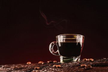 Coffee cup and coffee beans spread on red background on wooden table