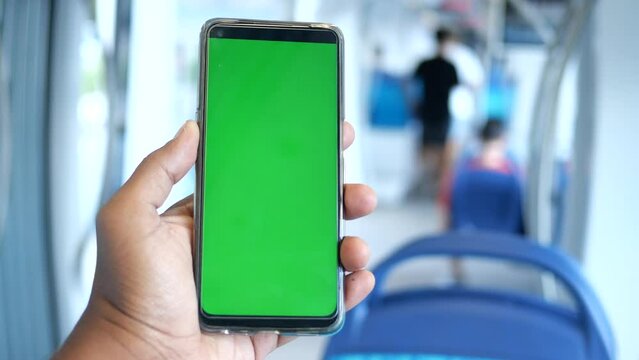 young man hand using smart phone with green screen inside of metro train